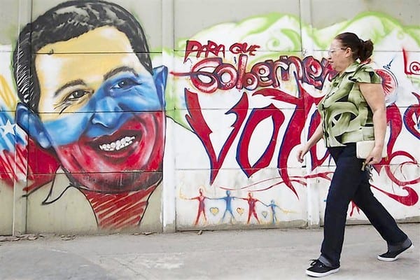 A woman walks past a mural depicting Venezuelan President Hugo Chavez in Caracas