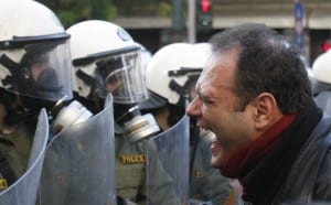 Greek demonstrator screaming at the impersonal, robotic forces of the system.