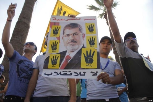 Protesters hold a poster of ousted Egyptian President Morsi, Cairo, September 20, 2013 (Wikipedia)